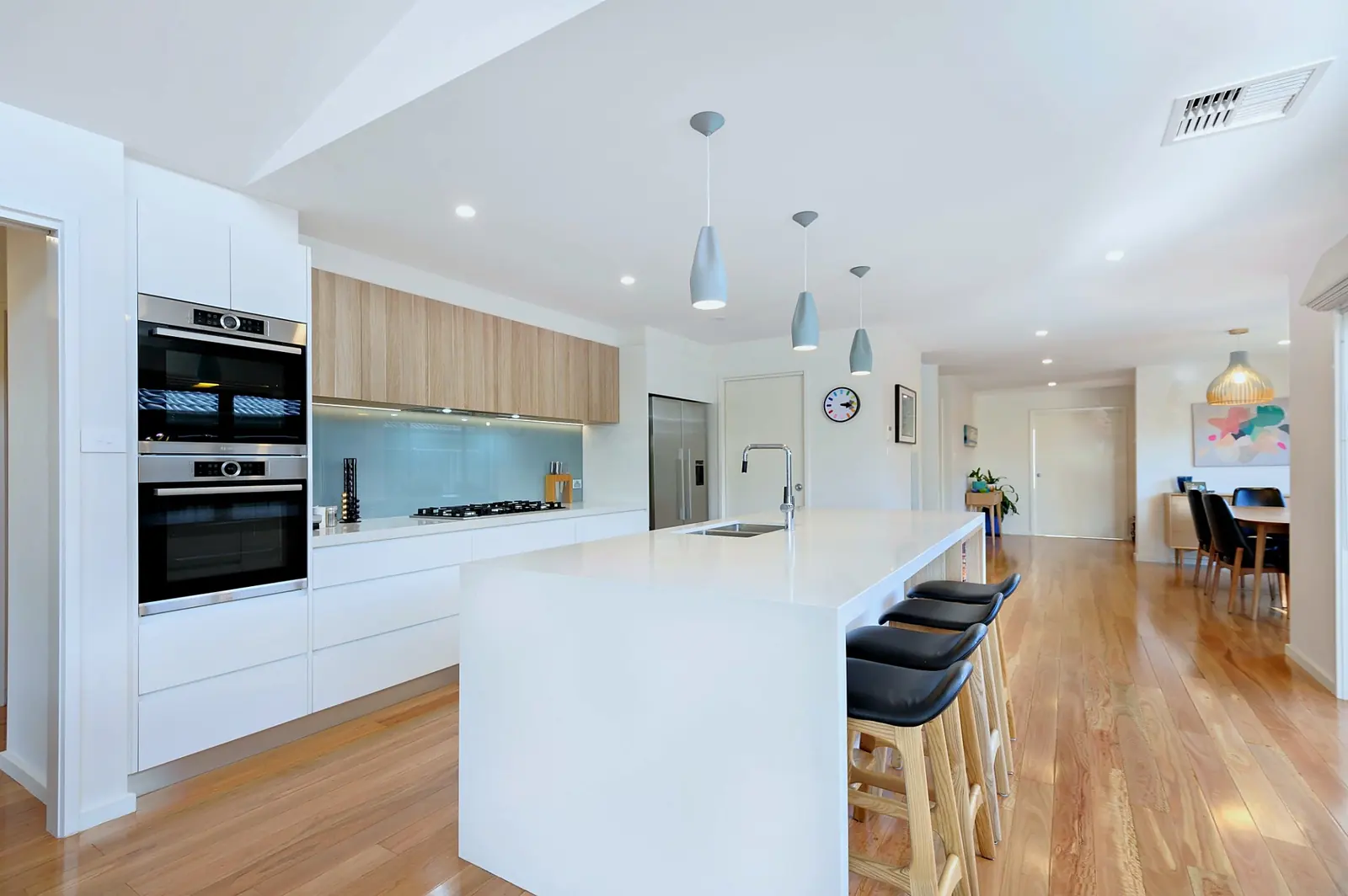 Open plan kitchen with stone island bench, timber floors and dining beyond