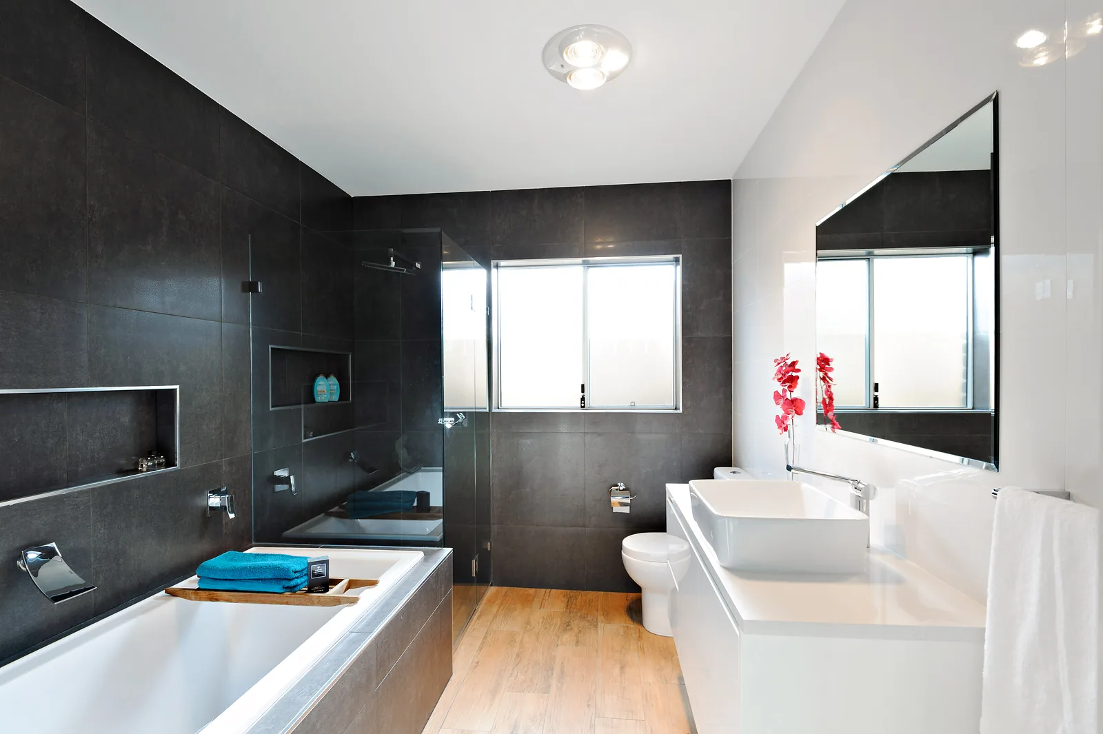 Main bathroom with charcoal feature tiles, inset bath and frameless shower