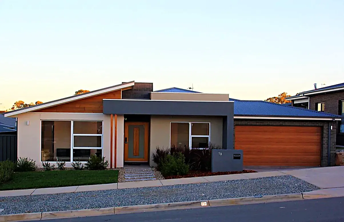 Completed family home with skillion roof and timber garage door at dusk, Canberra ACT