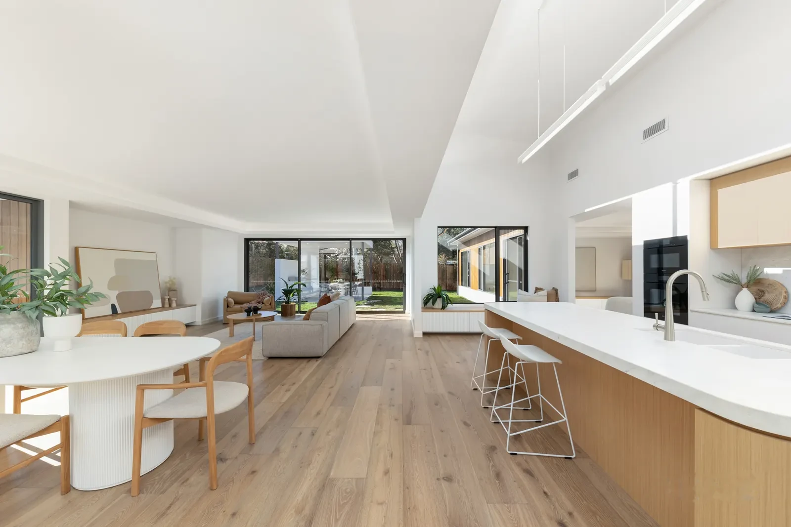 Open plan living, dining and kitchen under a raked ceiling with highlight glazing